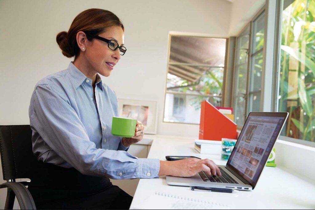 A customer of our optical retail franchise enjoying her glasses as she works in her home office.