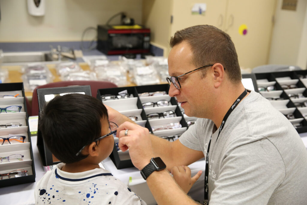 ABSee rep trying glasses on a child.