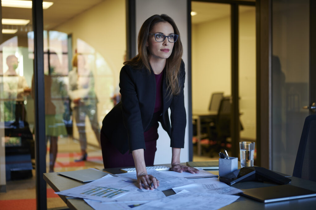 Professionally dressed woman at a desk with papers on it