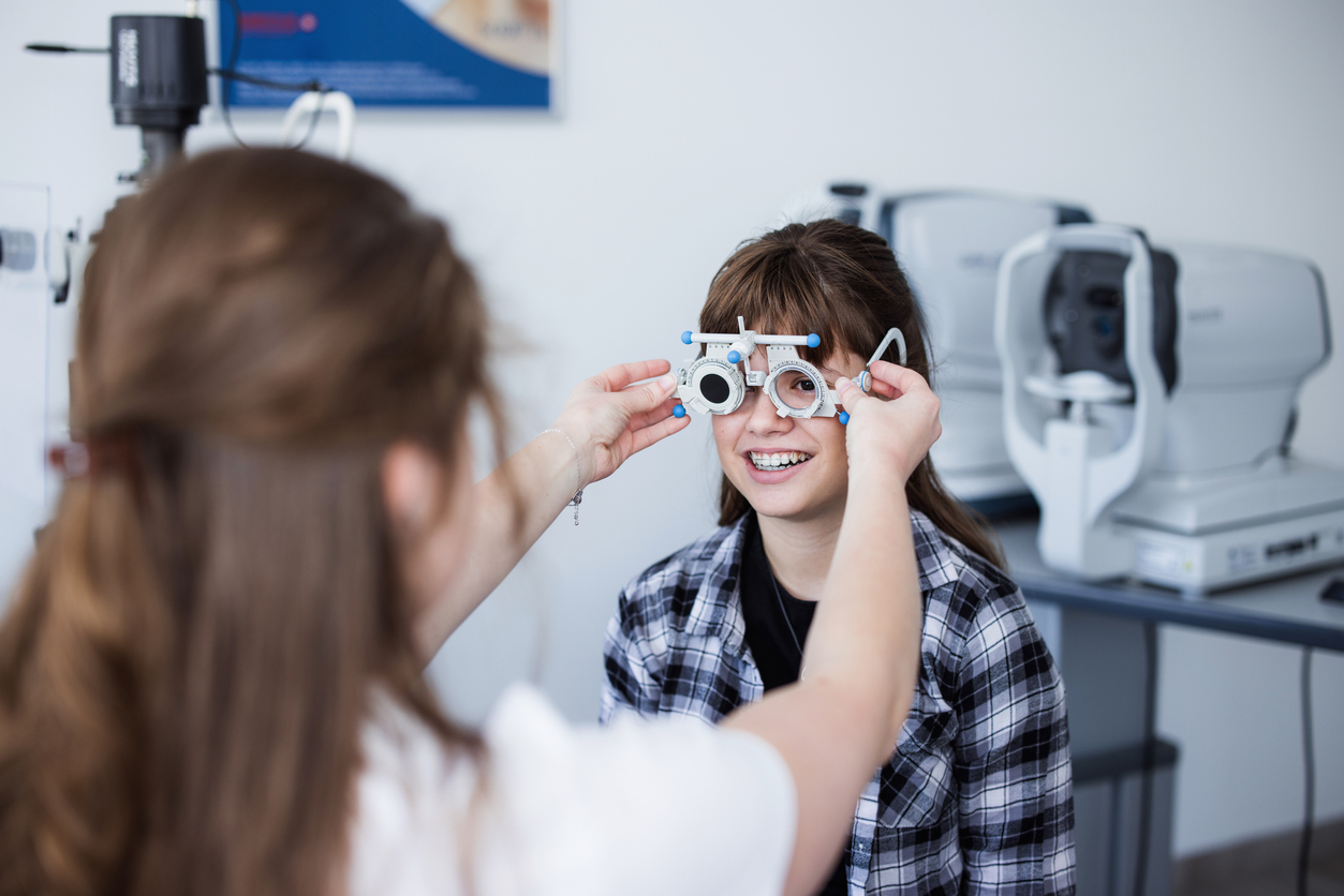 Teenage girl sitting at doctor's office and having her eyesight checked