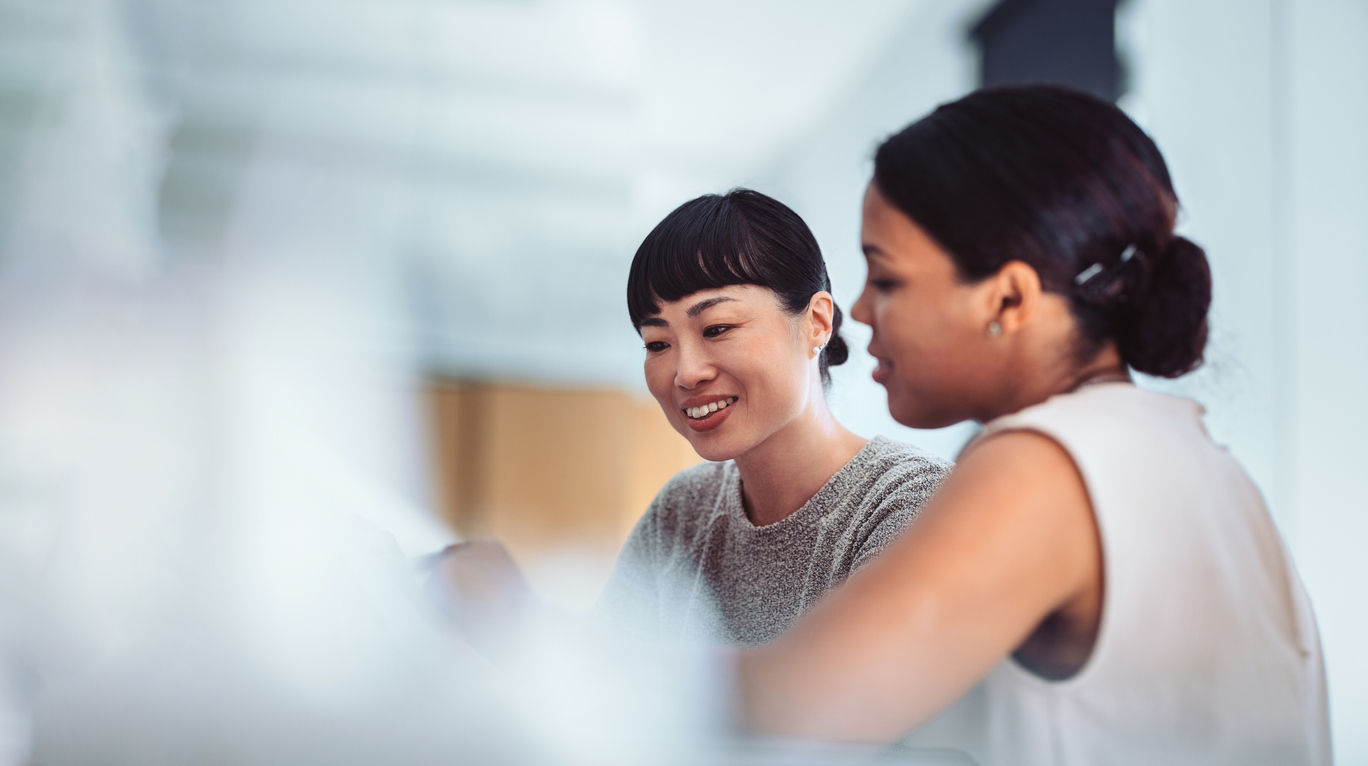 Two professional women engaged in a collaborative discussion in a modern office setting. Concept of teamwork, business, and office communication.