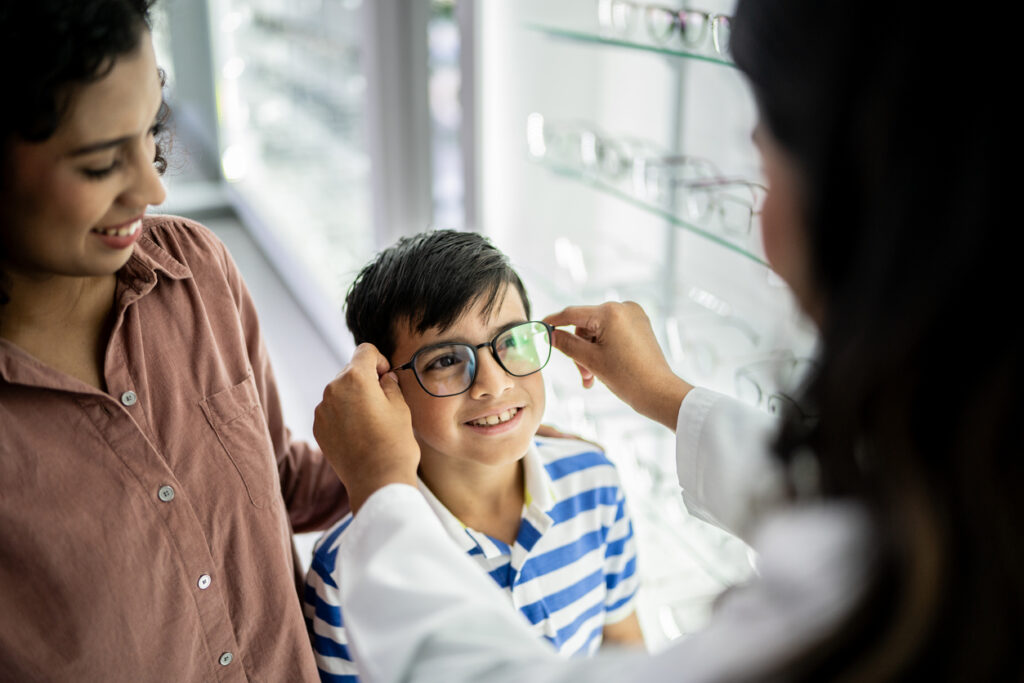 Mother and son buying a glasses and talking with optician at optics